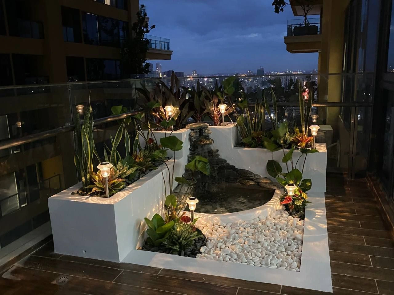 Luxury balcony water feature with custom stone waterfall overlooking the Phnom Penh city skyline at night
